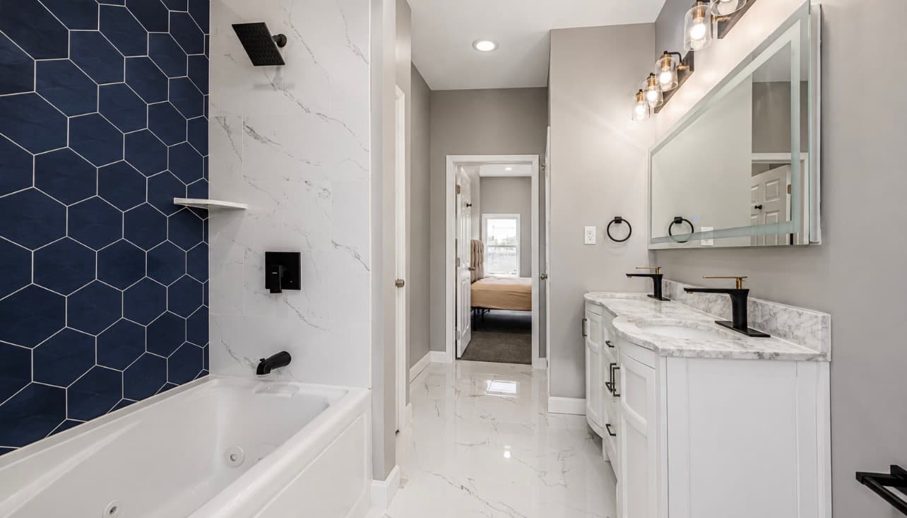Primary bathroom remodel with blue tile surround, double vanity, and marble surfaces